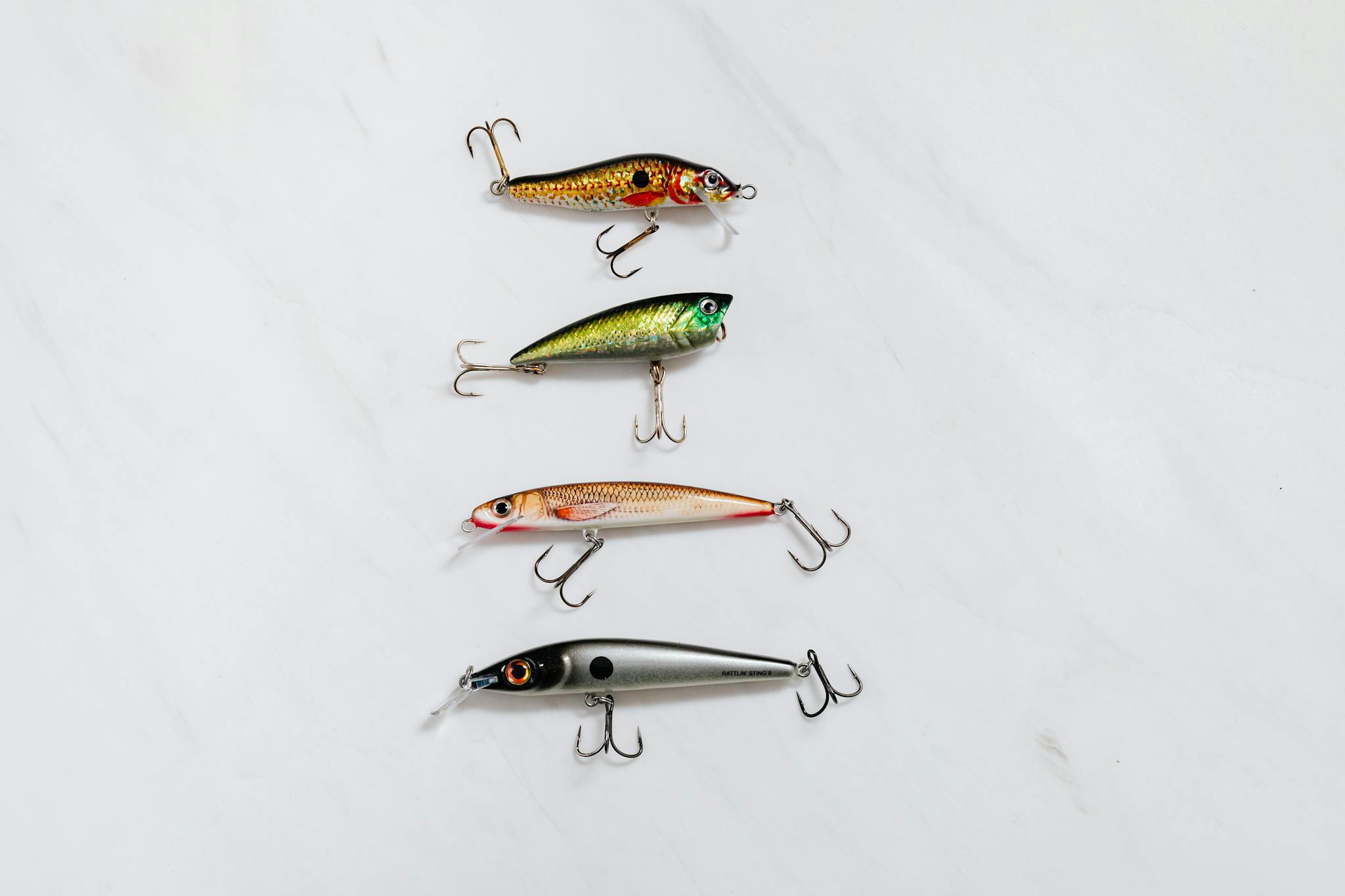 Variety of fishing lures arranged on a white surface for equipment showcase.